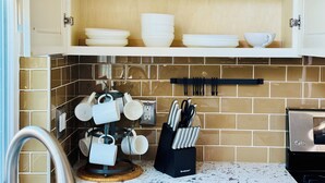 A kitchen with a wooden shelf holding white mugs and bowls, a mug rack with white cups, and a knife block with utensils. - Luxurious, Beautiful and Comfy 4-bedroom house with in the heart of San Jose (San Jose)