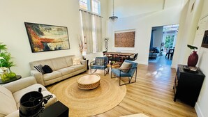A spacious living room with a large sofa, a coffee table, and a dining area with a wooden table and chairs. - Luxurious, Beautiful and Comfy 4-bedroom house with in the heart of San Jose (San Jose)