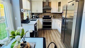 A modern kitchen with white cabinets, a stainless steel refrigerator, and a large window. - Luxurious, Beautiful and Comfy 4-bedroom house with in the heart of San Jose (San Jose)