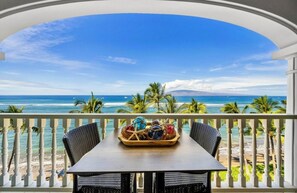 Een balkon met uitzicht op de oceaan en palmbomen.