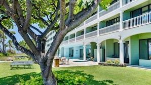 A two-story building with a covered outdoor area, a swimming pool, and a well-maintained lawn. - Lahaina Shores Beachfront Condo with Panoramic Endless Ocean Views (Lahaina)