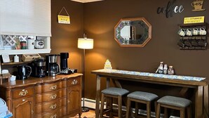 Una cucina con angolo caffè, un tavolo da pranzo con sedie, una lampada e uno specchio a parete.