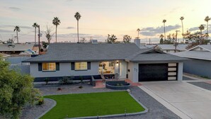 A single-story house with a garage, a well-maintained lawn, and a clear view of the surrounding neighborhood. - New! Modern Home on Mill Ave. Pool. Pet Friendly. (Tempe)