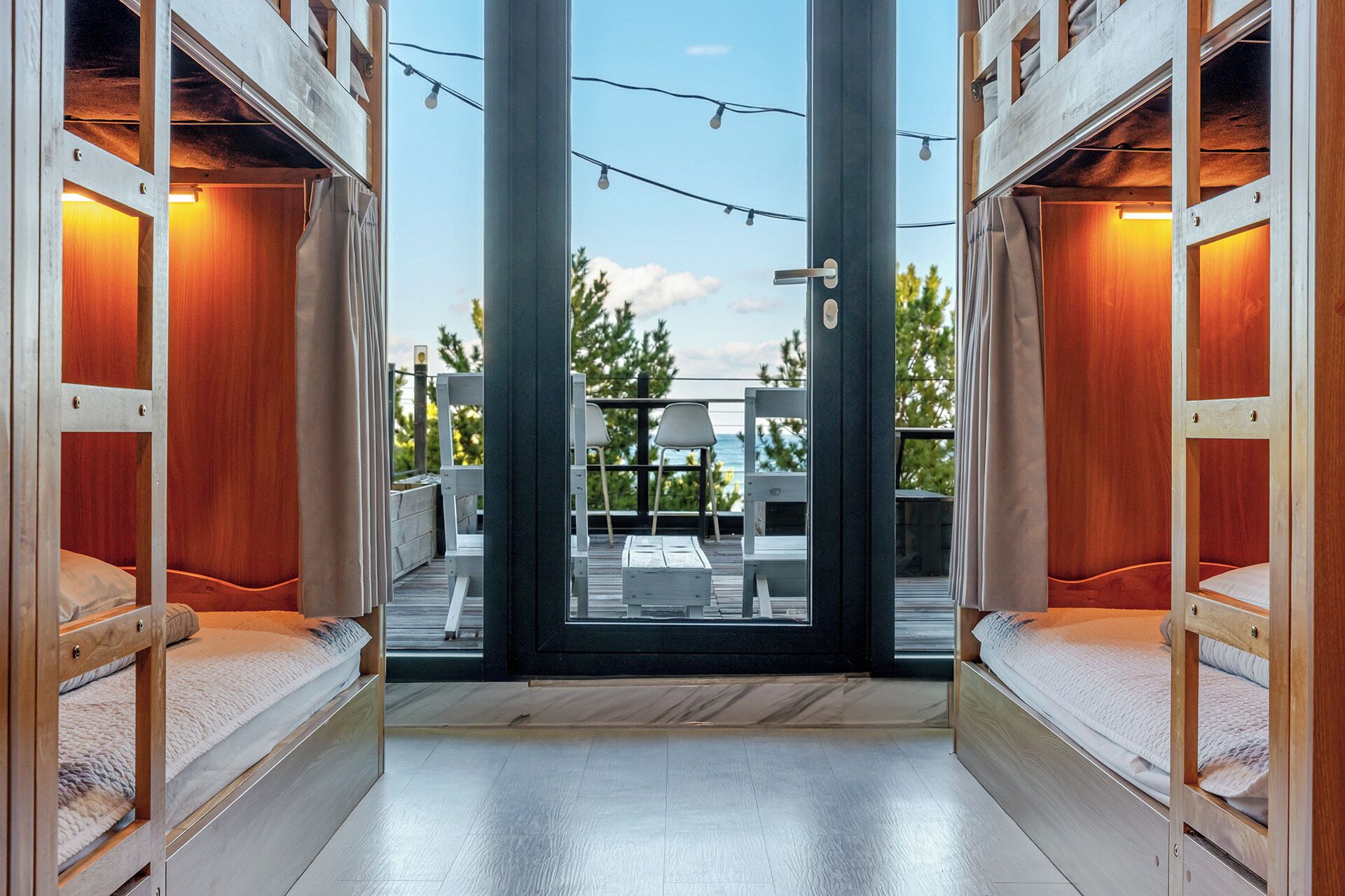 A modern interior with a central door leading to an outdoor area, wooden furniture, and a view of the outdoors.