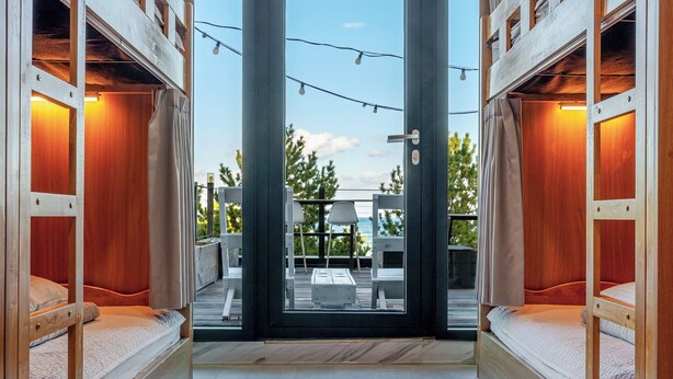 Un intérieur moderne avec une porte centrale donnant sur un espace extérieur, des meubles en bois et une vue sur le paysage.
