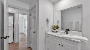 A modern bathroom with a white sink, mirror, and storage cabinets.