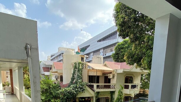 A balcony with a view of a residential area, including houses and a modern building.