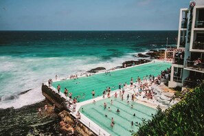 Ein großer Außenpool mit klarem, türkisblauem Wasser, umgeben von Felsklippen und mit Blick auf den Ozean.