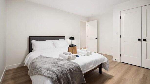 A neatly made bed with white linens, a bedside lamp, and a folded towel on the bed. - The Silo 3 - Lofi Vibes (Morton)