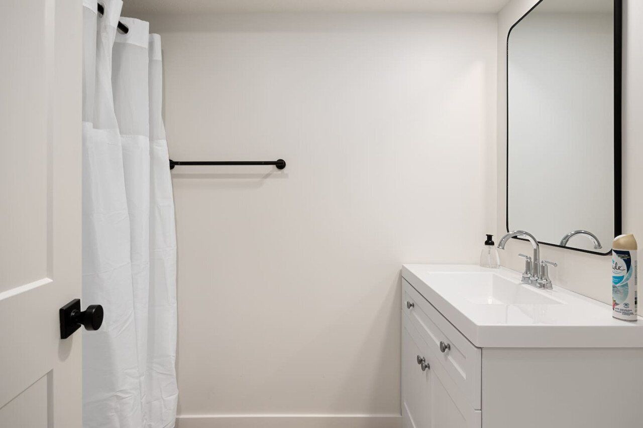 A bathroom with a white sink, a mirror, and a shower curtain.