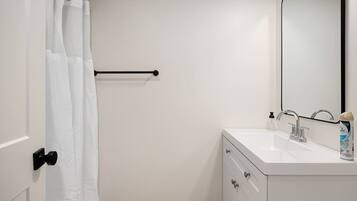 A bathroom with a white sink, a mirror, and a shower curtain.