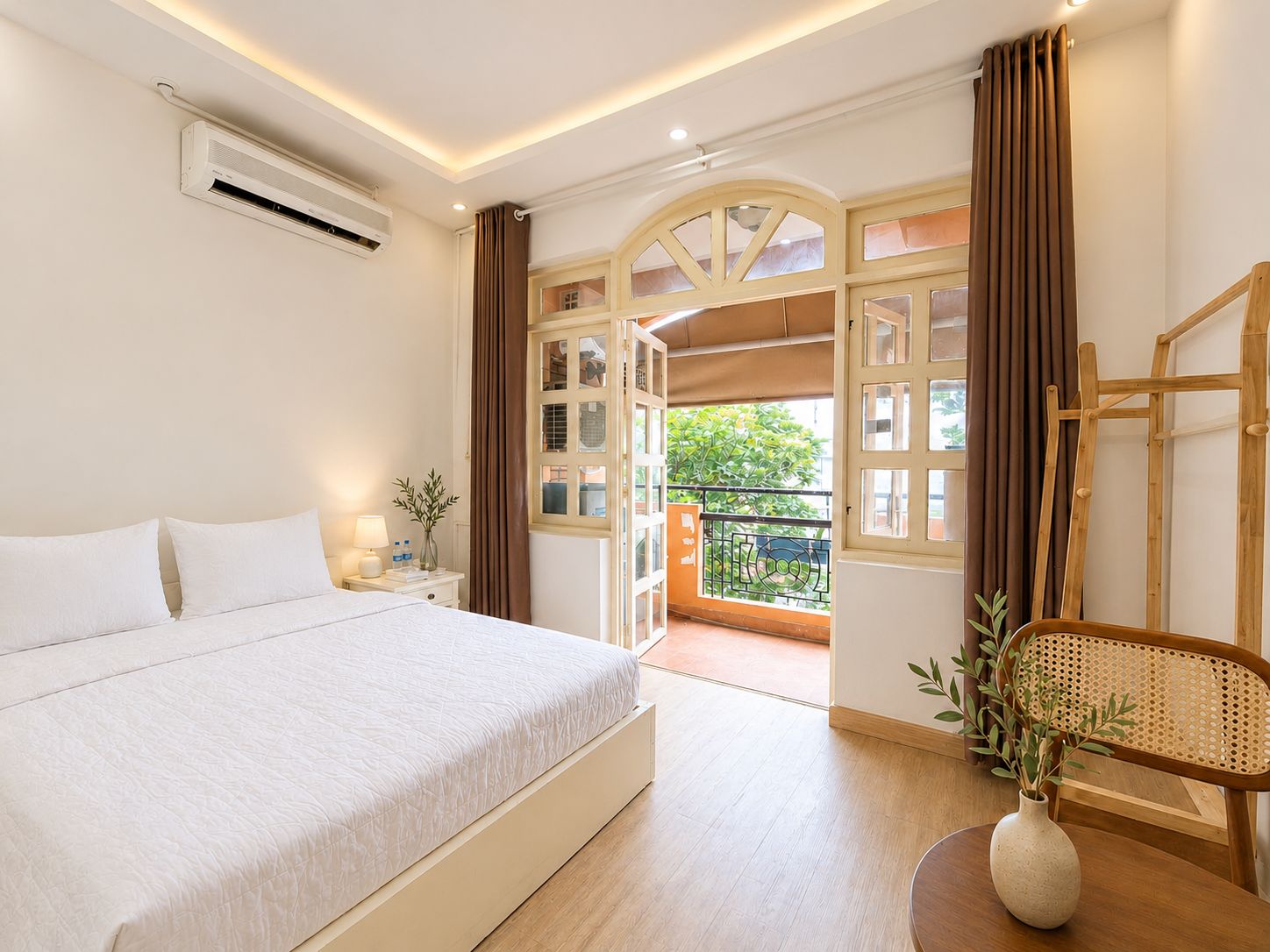 Ein Hotelzimmer mit Bett, Nachttisch, Lampe und Blick ins Freie.