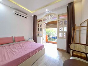A bedroom with a bed, a chair, a window, and an air conditioning unit. - Lunaria NEST - Saigon Corner, Tan Dinh (Ho Chi Minh City)