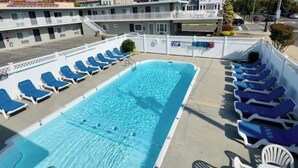 En swimmingpool med solstolar och ett bord, omgiven av byggnader.