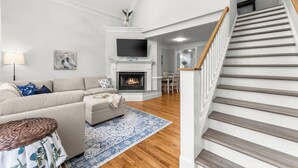 Ein Wohnzimmer mit Sofa, Kamin, Fernseher und einer Treppe.