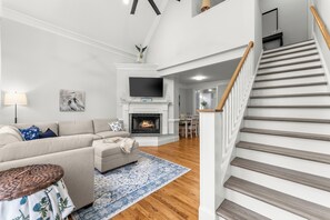 Ein Wohnzimmer mit Sofa, Kamin, Fernseher und einer Treppe.