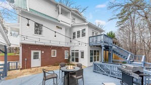 Eine Terrasse mit Feuerstelle, Gartenmöbeln und Grill.