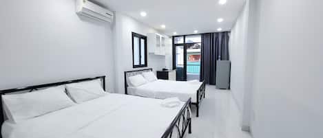 A hotel room with two beds, a window, an air conditioning unit, and a view of the outside.