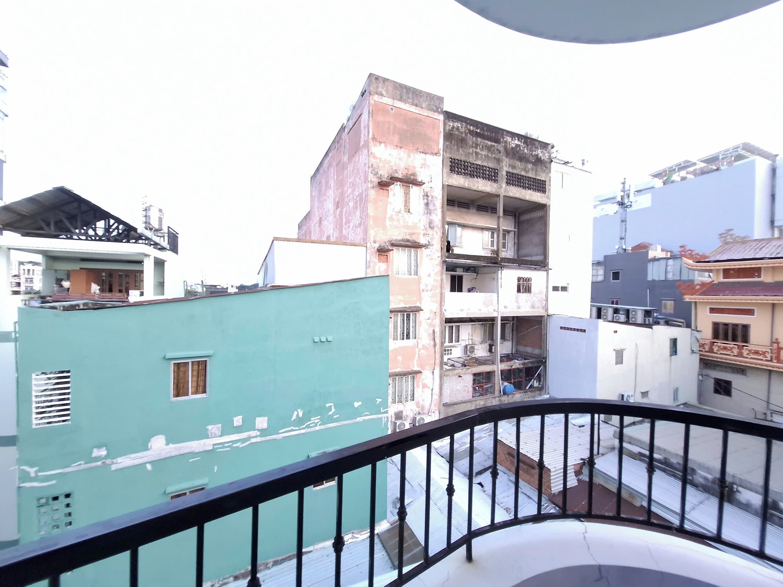 A multi-story building with visible balconies and a green facade.