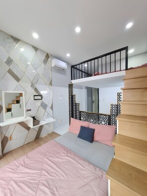 Une chambre avec un lit superposé, une table de chevet, un miroir et un mur décoré d’un motif.