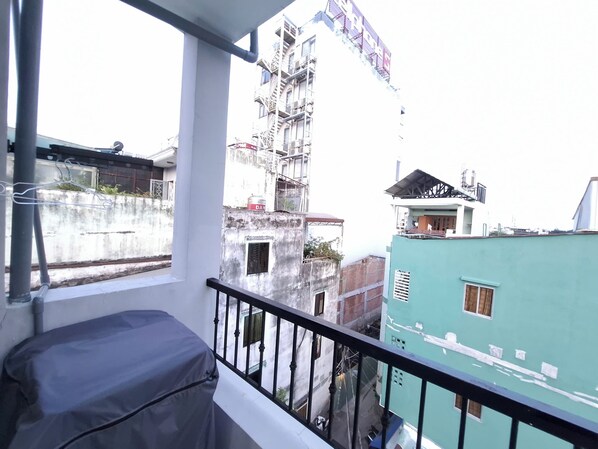 A balcony with a covered seating area, a view of adjacent buildings, and a partially constructed building with scaffolding. - Lunaria Group - Saigon Loft Stay (Ho Chi Minh City)
