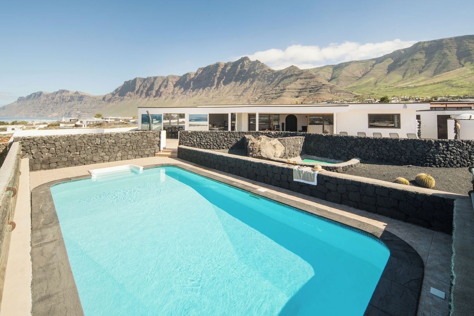 A swimming pool with a stone wall and a view of mountains.