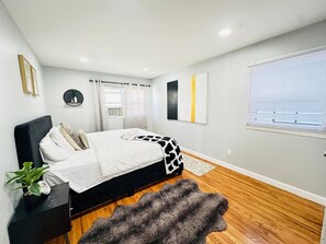 Un dormitorio moderno con cama, mesita de noche y un ventanal grande.