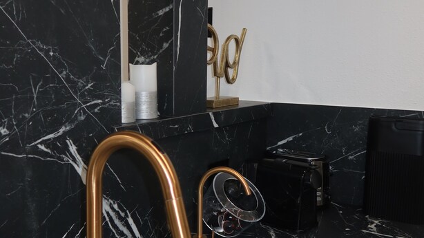 A modern bathroom with a black marble sink, gold fixtures, and a black marble backsplash. - Modern 1 bedroom apartment in Glendale near The Americana at Brand (Glendale)