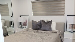 A modern bedroom with a large bed, two bedside tables, a mirror, and a ceiling light. - Modern 1 bedroom apartment in Glendale near The Americana at Brand (Glendale)