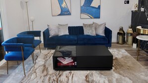 A modern living room with a blue sofa, two blue armchairs, a glass coffee table, and abstract paintings on the wall. - Modern 1 bedroom apartment in Glendale near The Americana at Brand (Glendale)