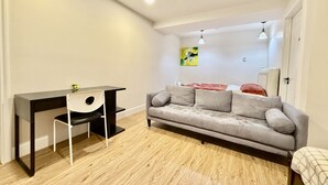 Una sala moderna con un sofá gris, un escritorio negro y una silla blanca.