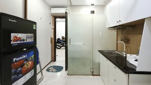 Eine kleine Küche mit Kühlschrank, Spüle und einer Tür zu einem weiteren Raum.