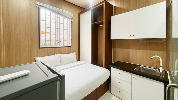 Ein Schlafzimmer mit Bett, Schreibtisch, Kleiderschrank und einem Bad mit Waschbecken.
