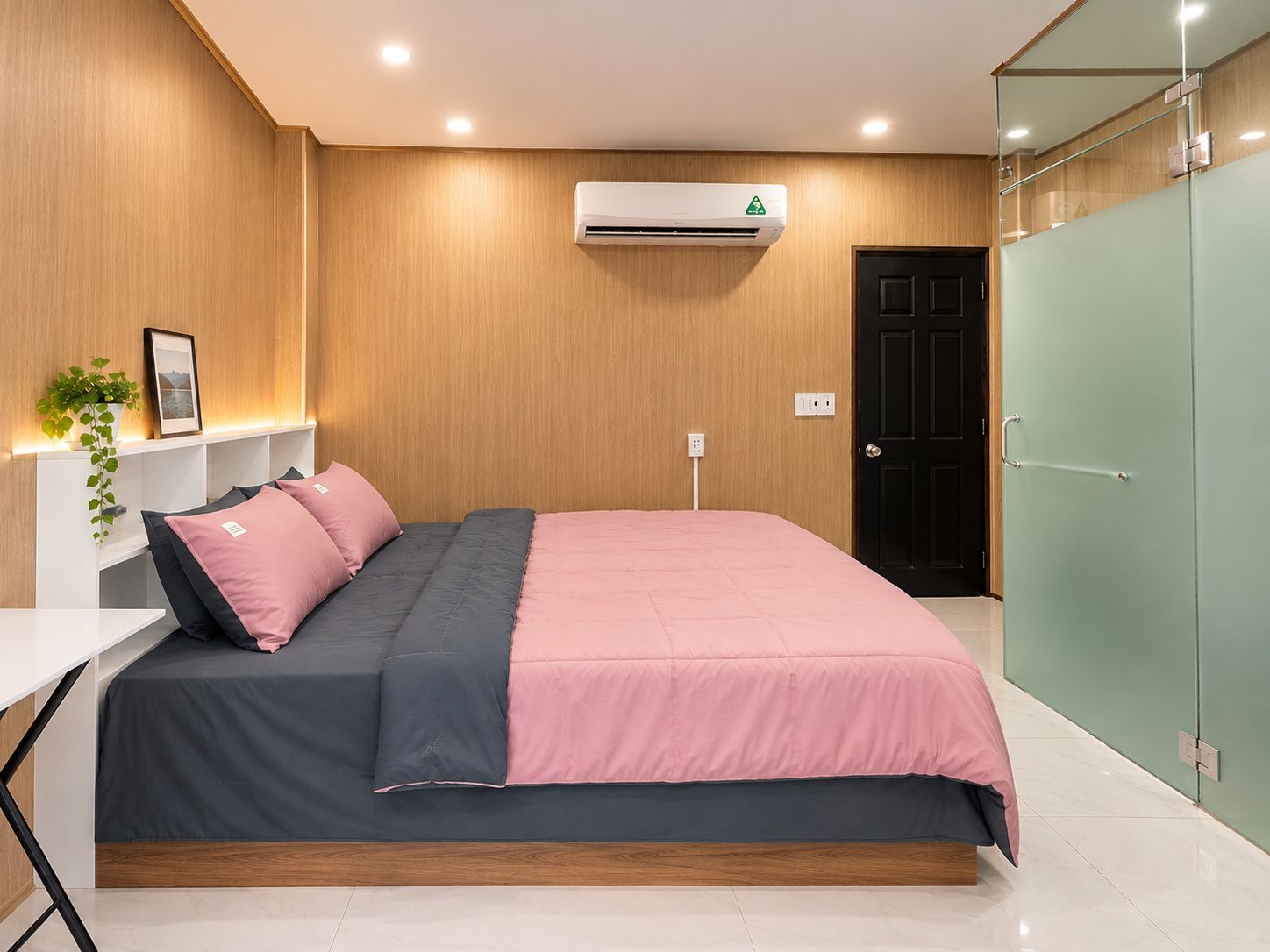 A modern bedroom with a bed, bedside table, and a wall-mounted air conditioner.