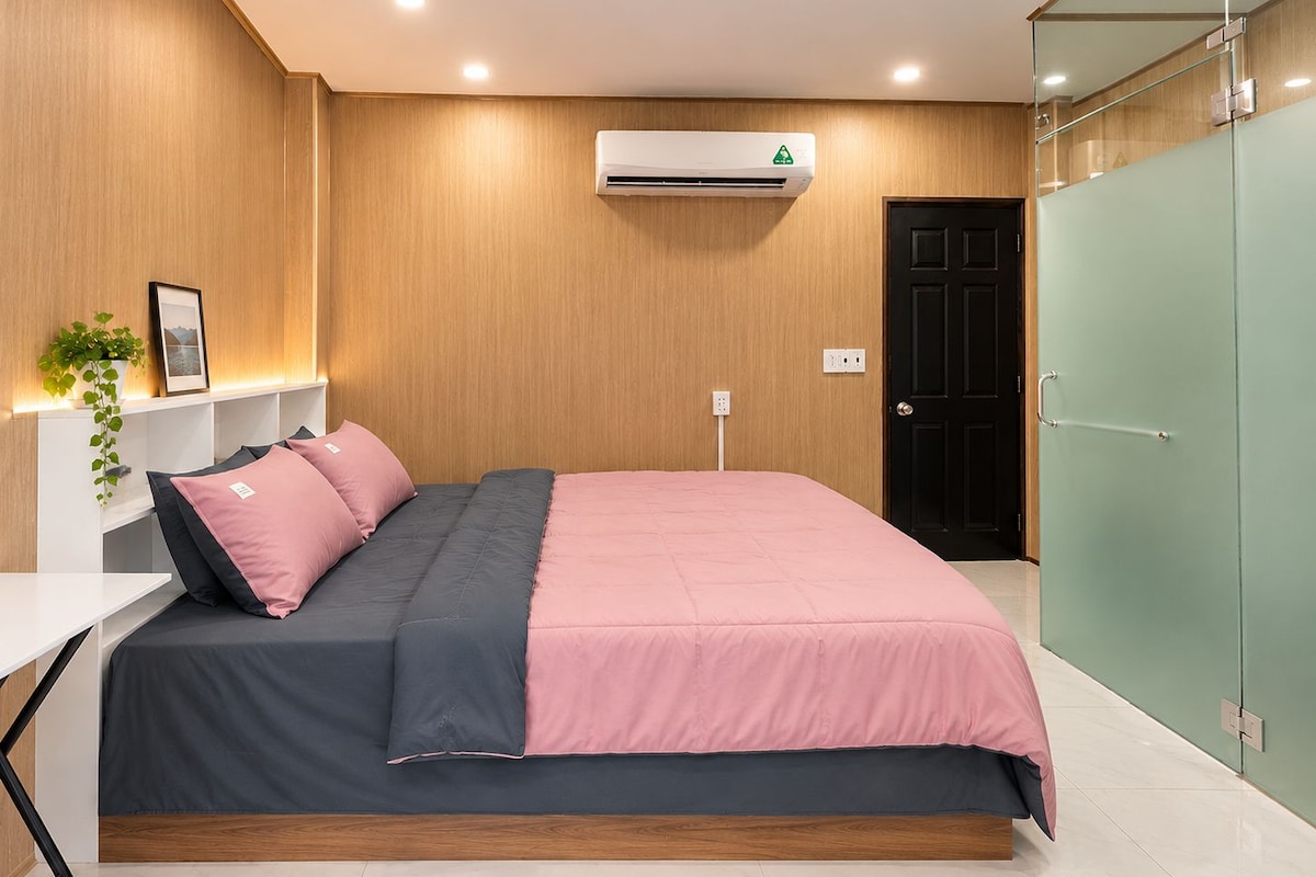 A modern bedroom with a bed, bedside table, and a wall-mounted air conditioner.
