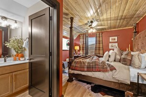 Een slaapkamer met een houten plafond, een bed met een geruite plaid, een nachtkastje en een spiegel.