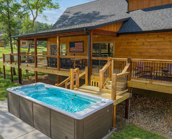 Een hottub met een houten terras en een overdekte patio.