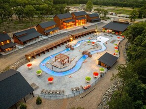 Ein Resort mit mehreren Holzhütten, einem zentralen Poolbereich und Sitzgelegenheiten im Freien.