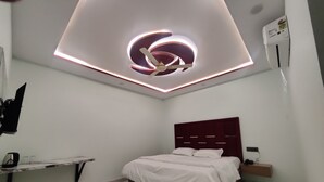 Une chambre moderne avec un lit, un luminaire au plafond et un climatiseur fixé au mur.