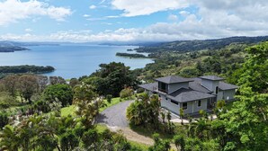 A modern house with a view of a lake and surrounding greenery. - Panoramic Lake Arenal Sunset View Villa with AC (Nuevo Arenal)