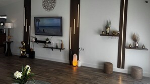 Un salon moderne doté d’un téléviseur à écran plat fixé au mur, d’un parquet et d’étagères décoratives ornées de plantes et de vases.