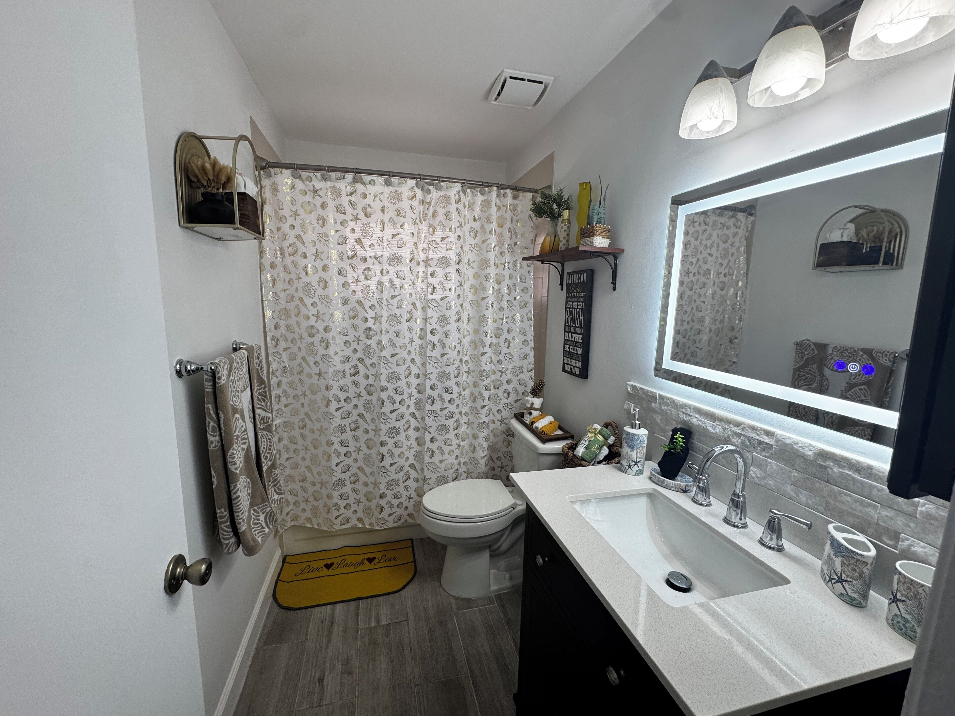 A bathroom with a toilet, sink, and shower curtain with a shell pattern.