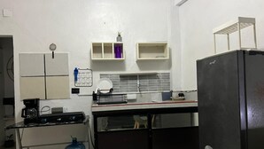 Une cuisine compacte équipée d’un réfrigérateur, d’une machine à café et d’un distributeur d’eau.