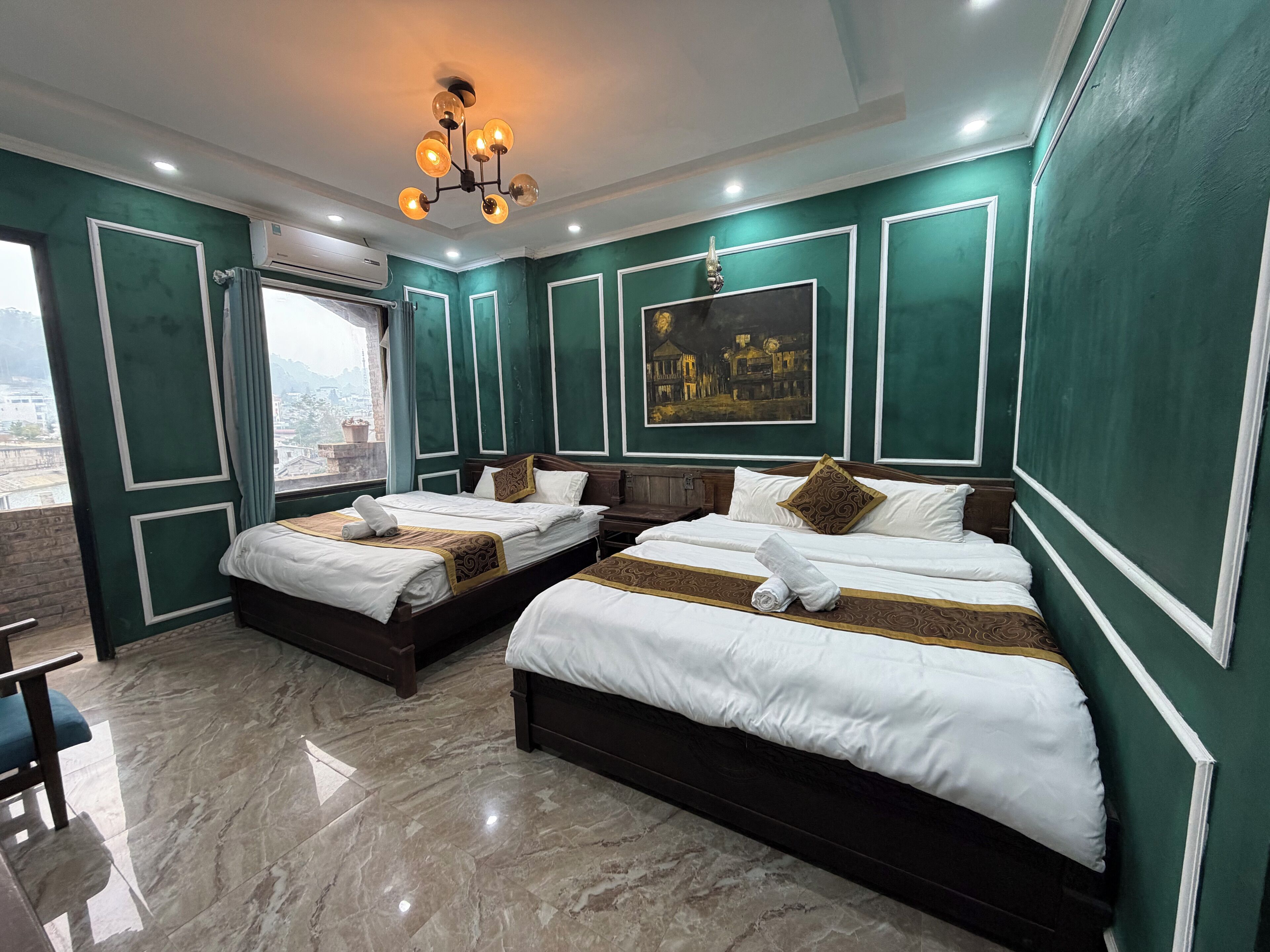 A hotel room with two beds, a large window, and a city view.