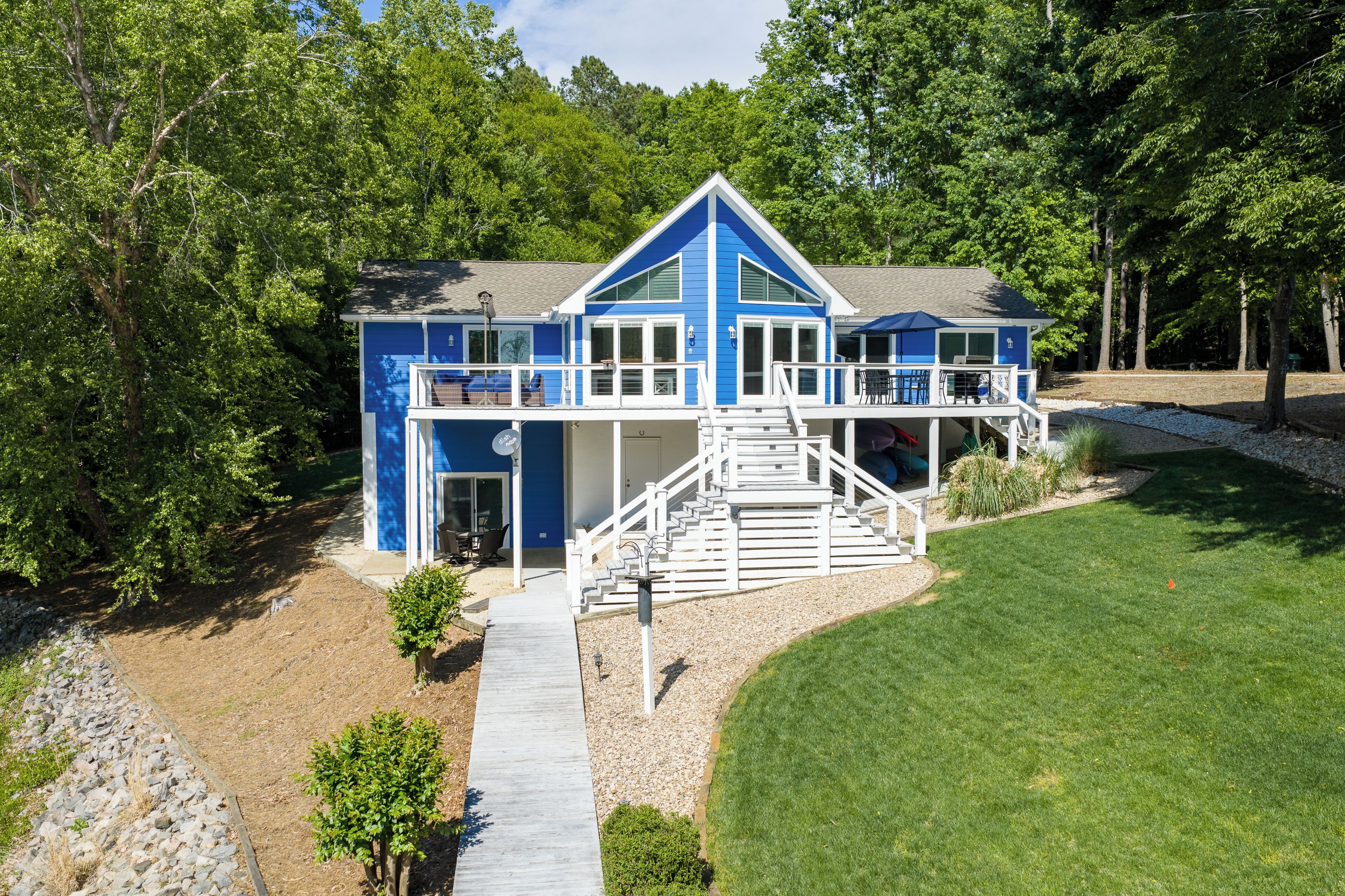 Une maison bleue avec un porche, un escalier et un chemin menant à l’entrée.