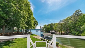 En terrass med utsikt över en sjö, en brygga och en liten byggnad.