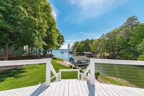 A deck with a view of a lake, dock, and a small building. - Wake and Lake - Prime Location, Stunning Views! (Littleton)
