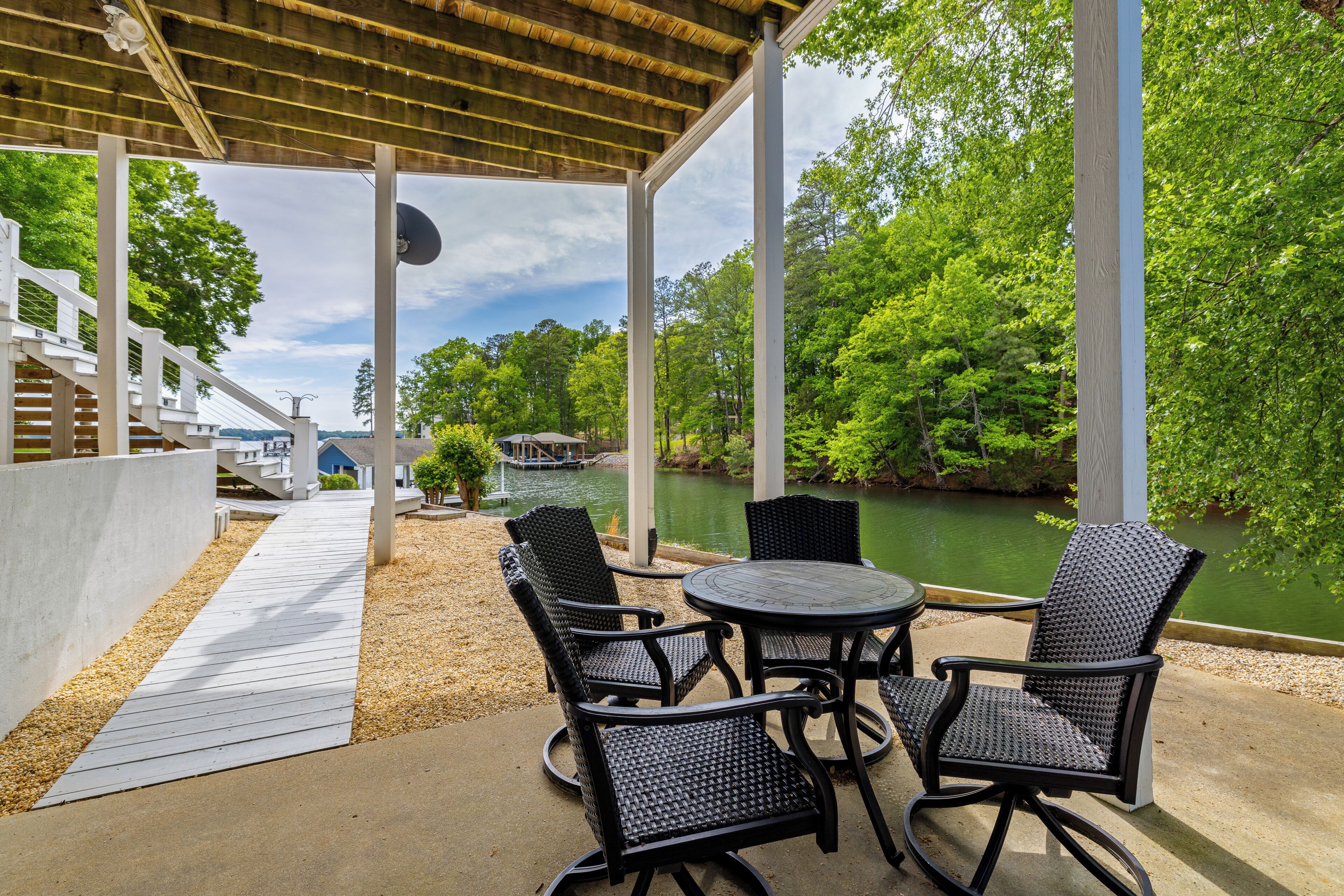 A covered outdoor seating area with a view of a lake and trees.