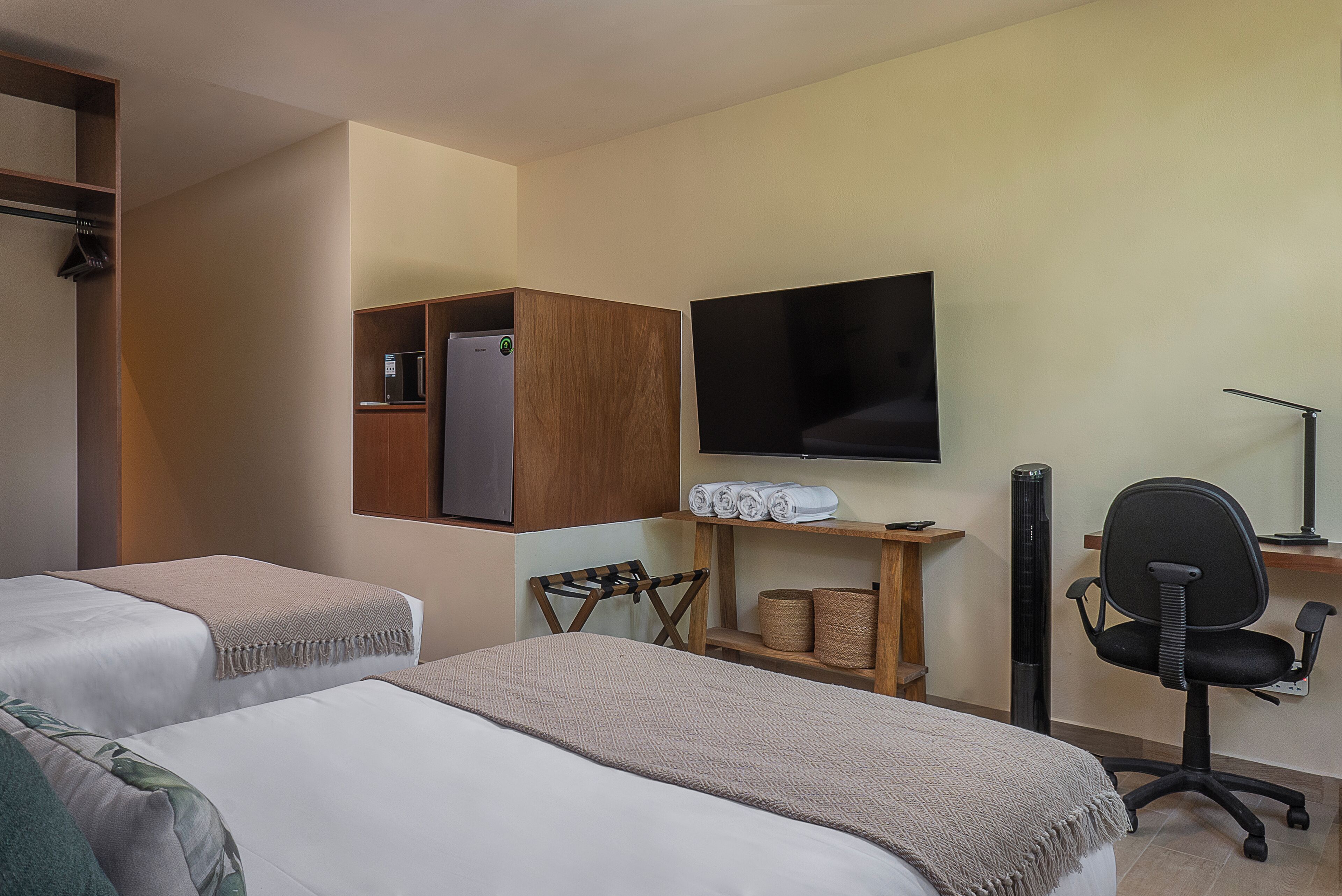Ein Hotelzimmer mit zwei Betten, einem Fernseher, einem Schreibtisch mit Stuhl und einem Kleiderschrank.