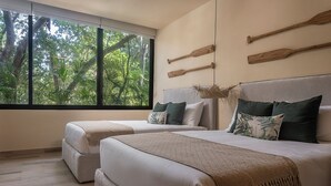 A bedroom with two beds, a large window with a view of trees, and wooden bathtowel holders on the wall. - Private Pool Paradise in Aldea Zama 2BR (Tulum)